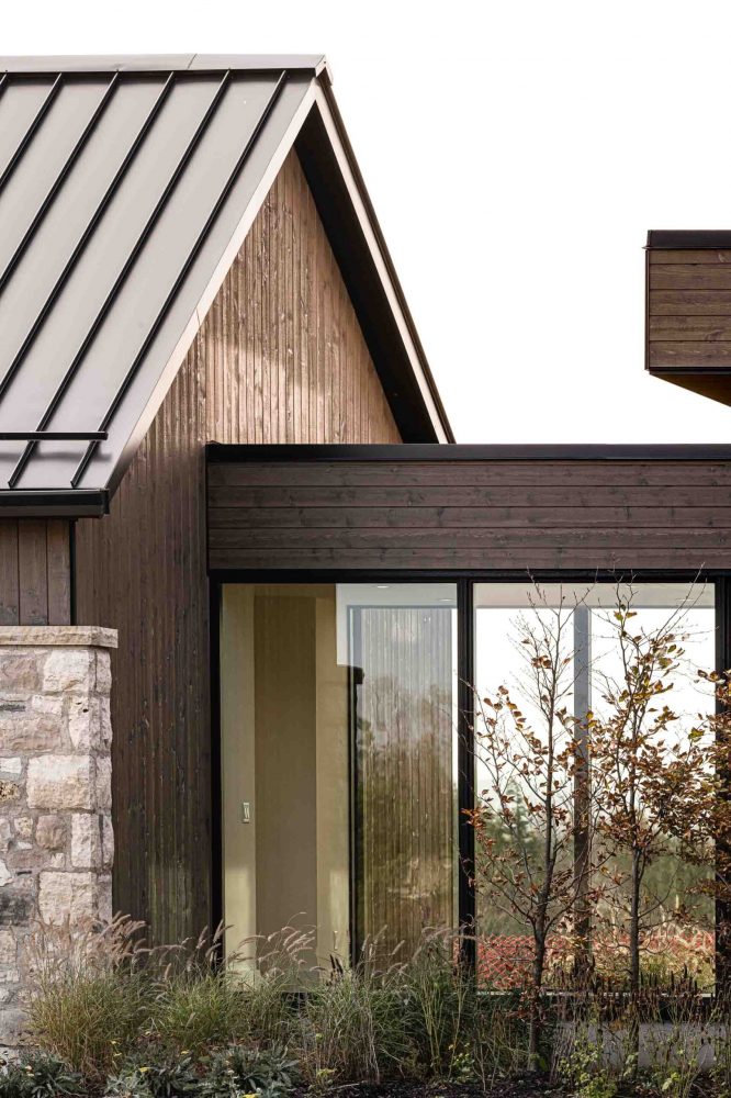 Exterior of a contemporary farmhouse showcasing the glass breezeway, stone and wood facade and modern lines