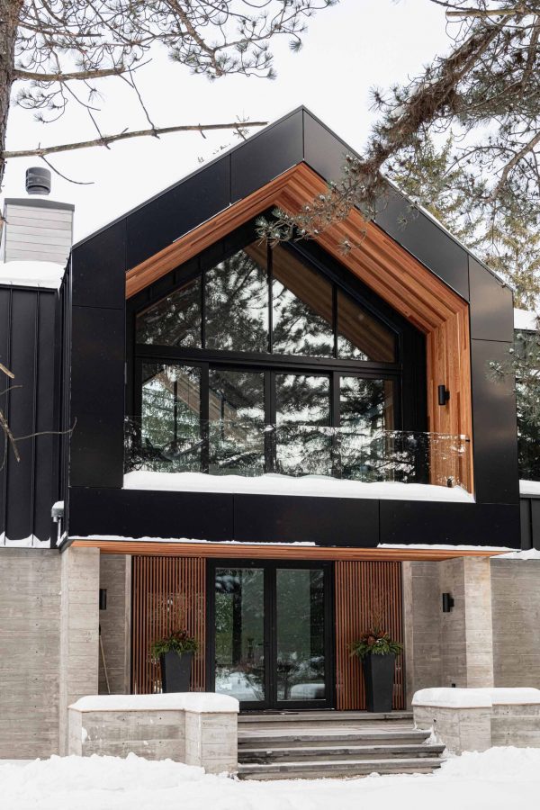 Modern alpine chalet with clean lines, board formed concrete walls, black metal siding, and rich wood detailing