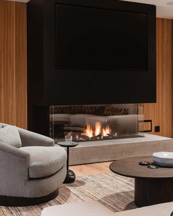 Modern concrete, glass and metal fireplace with integrated TV in a contemporary ski chalet