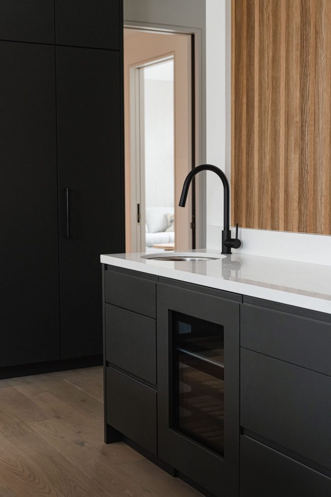 Modern Blue Mountain chalet kitchen detail with custom millwork, integrated wine fridge and bar sink with contemporary finishes