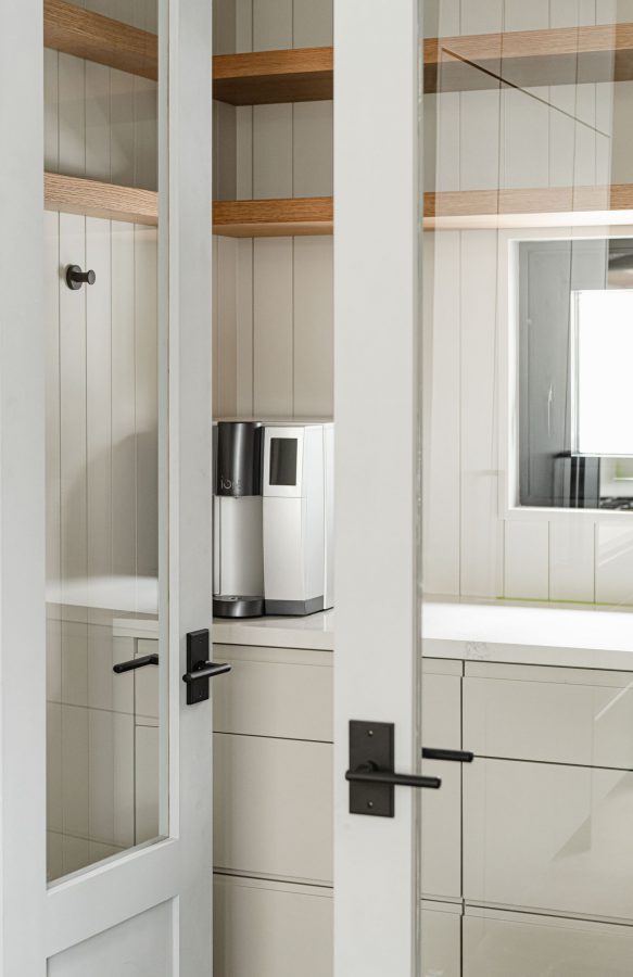 Modern ski chalet pantry detail with vertical shiplap walls, custom cabinetry and glass paneled doors
