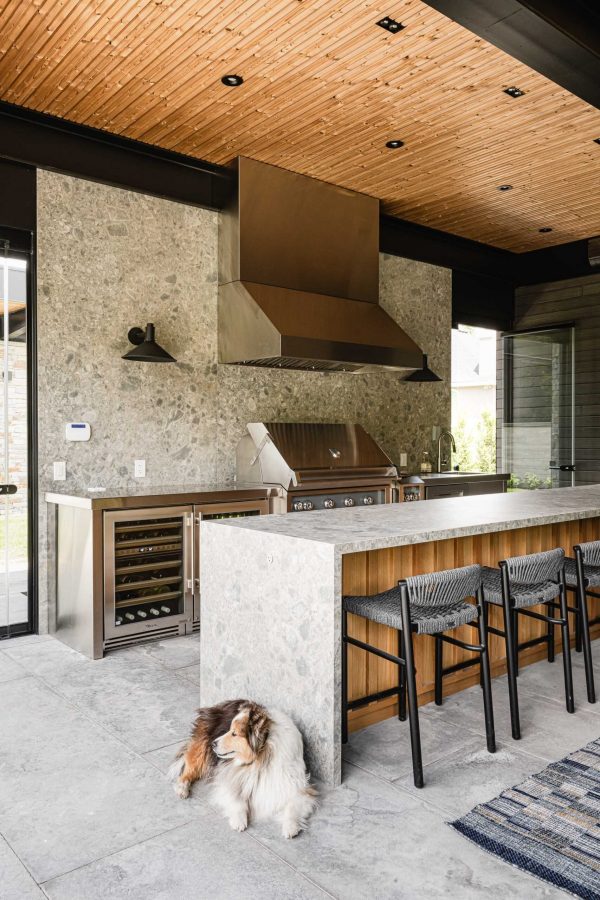 Modern Blue Mountain pool house with custom kitchen, bar seating, waterfall quartz island and backsplash, architectural wood and steel beam features