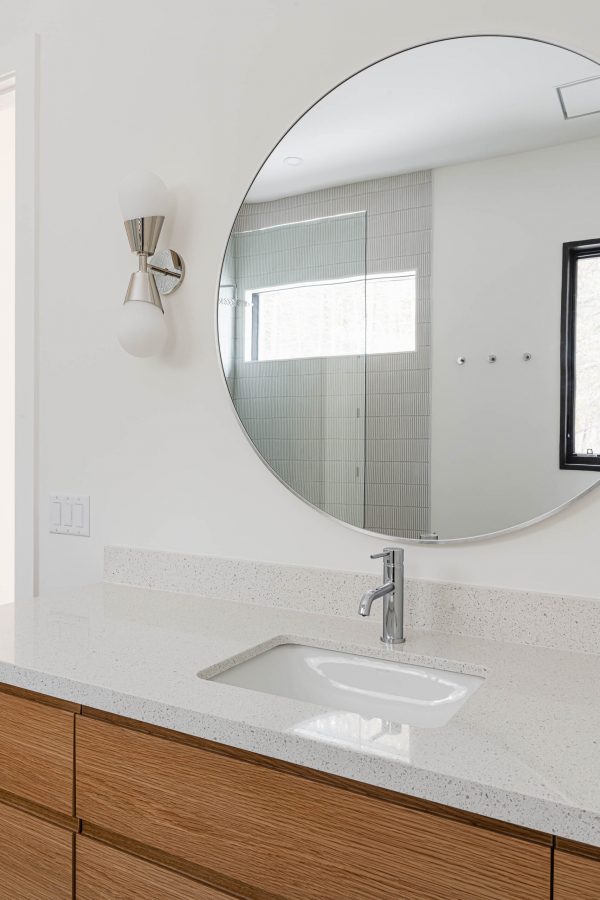 detail of a modern bathroom vanity with the shower reflected in the circular mirrror