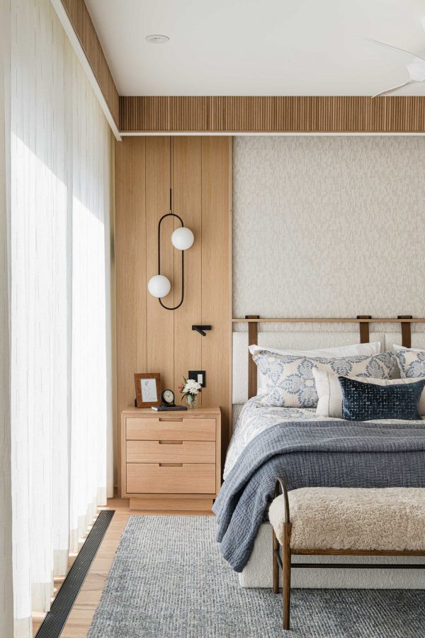 Modern chalet bedroom detail with custom upholstered headboard wall, fluted wood detailing and custom draperies