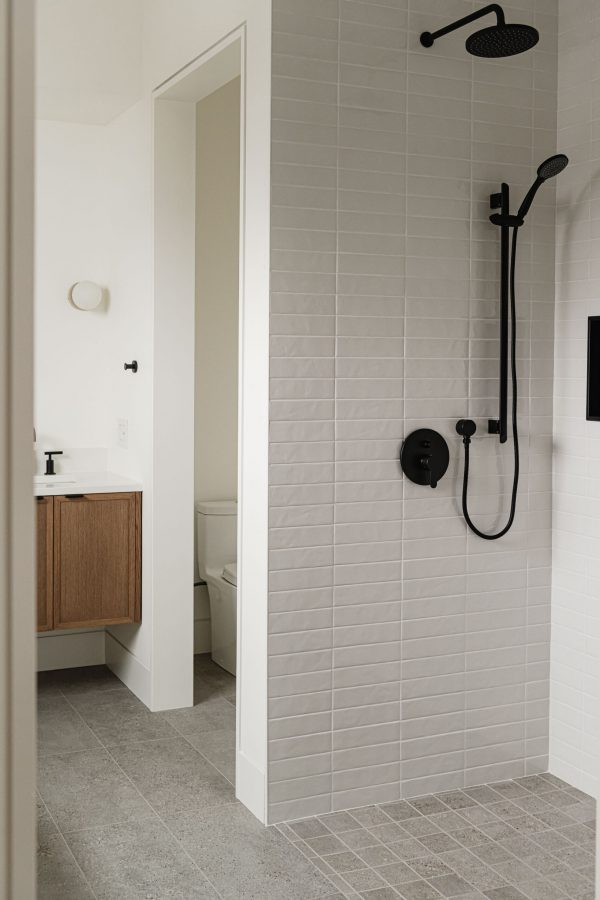 Modern chalet bathroom detail with curbless shower, textured subway tile and contemporary black finishes