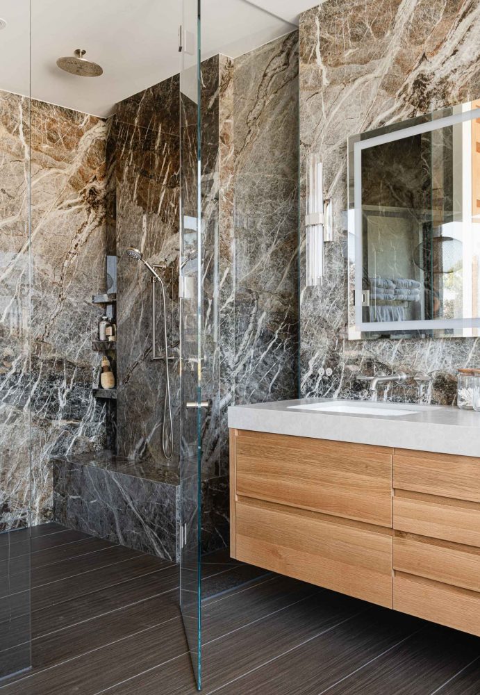 Contemporary chalet bathroom with rich, large format marble tiling, oversized glass shower, and modern finishes