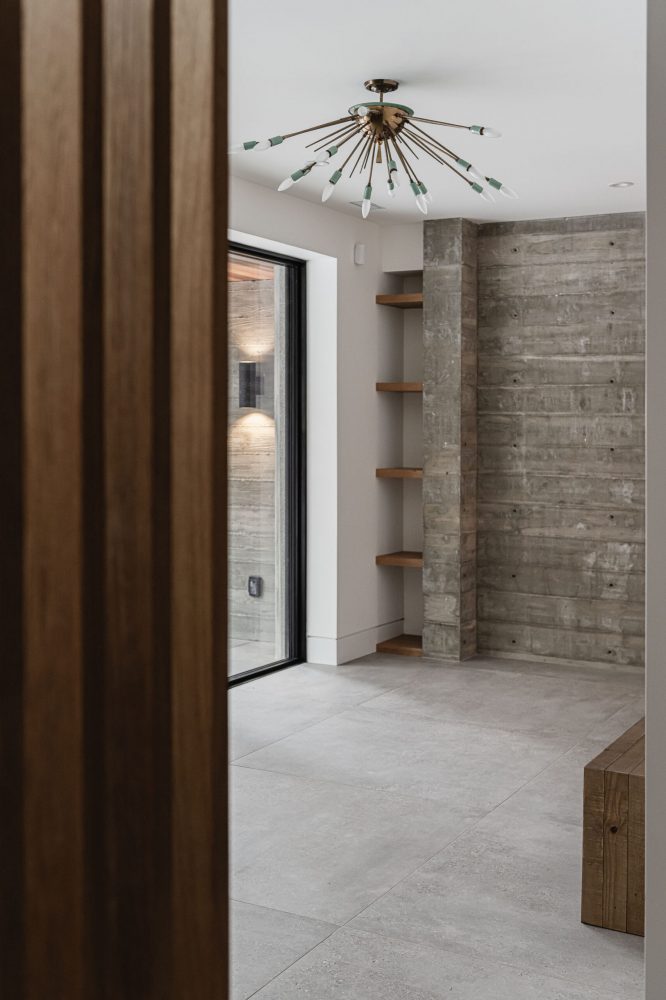 Modern ski chalet mudroom detail with heated, large-format floor tiles, board-formed concrete wall and wood details