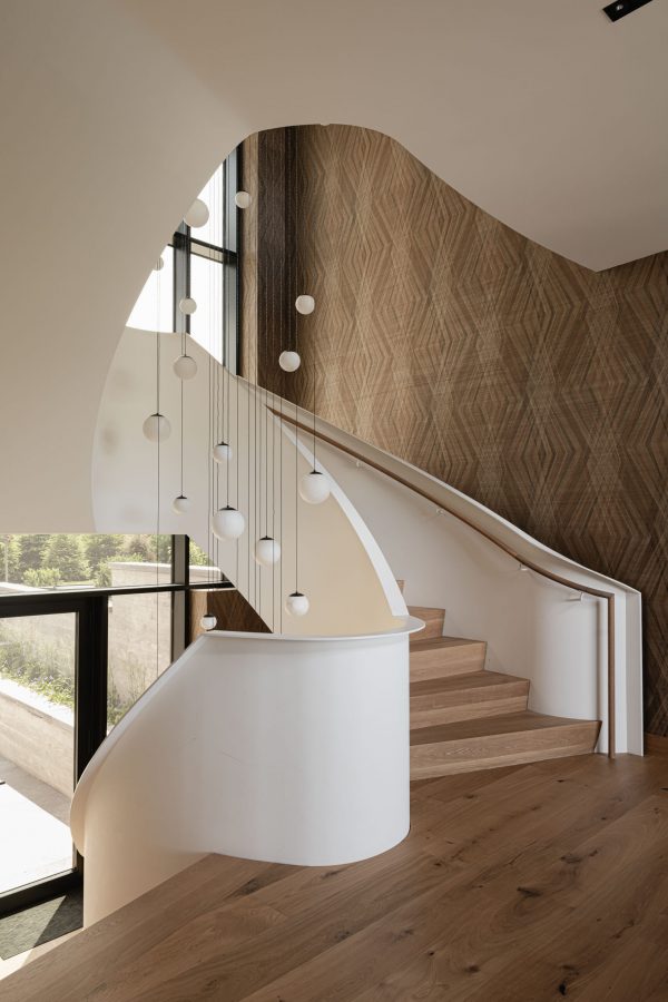 Freestanding, curved three-story steel staircase in a custom luxury home built by a Collingwood custom home builder