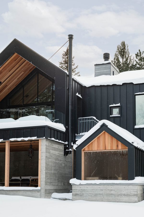 Contemporary Blue Mountain chalet rear elevation featuring board-formed concrete walls, black metal siding and attached sauna