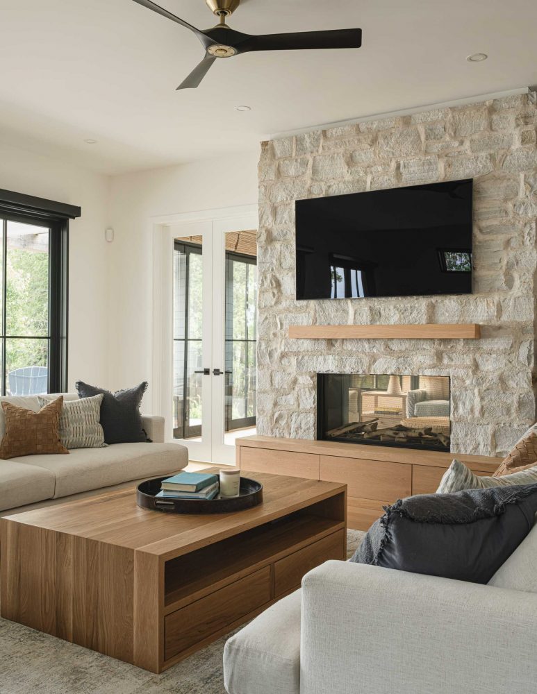 Natural tone fireplace and modern black framed wndows and doors on a waterfront modern beach house in The Blue Mountains