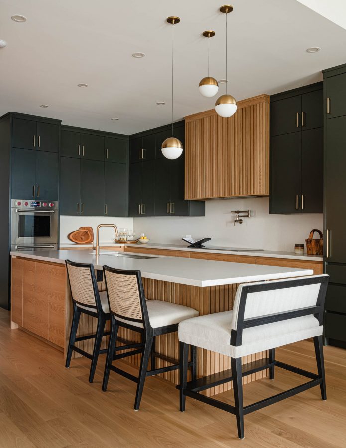 Contemporary kitchen in a custom built beach house with fluted wood detailing, and sleek charcoal custom cabinetry