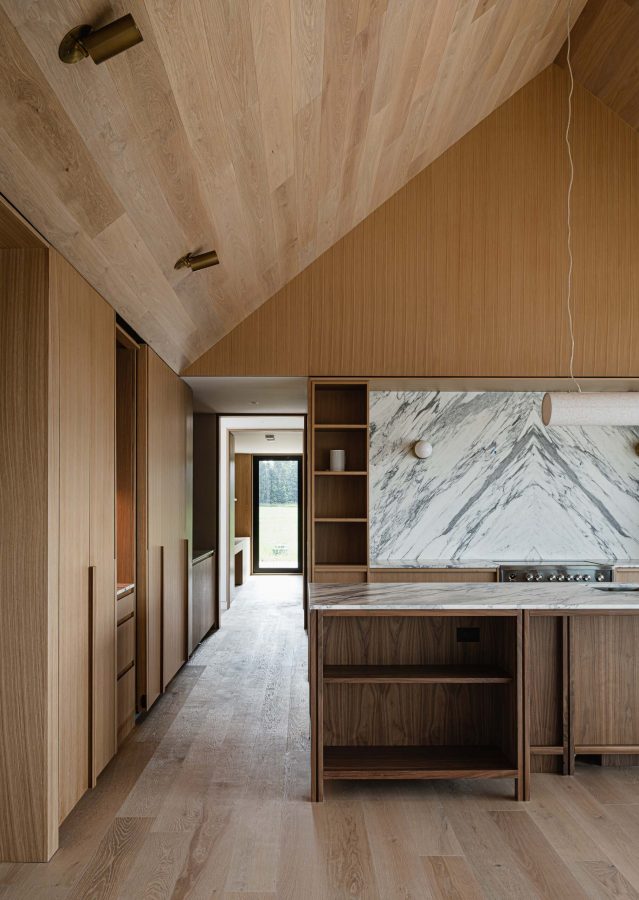 Sightline from a Scandinavian-inspired modern kitchen with custom millwork, bookmatched quartz backsplash and views through the hall to the study