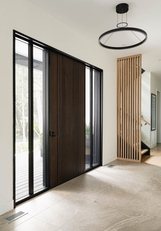 Foyer of a custom built Blue Mountain beach house with oversized wood door, modern light fixtures and wood detailing