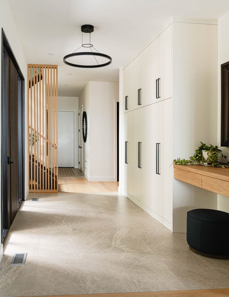 Foyer of a modern beach house with custom, full legth cabinetry, modern lighting fixtures, and wood detailing