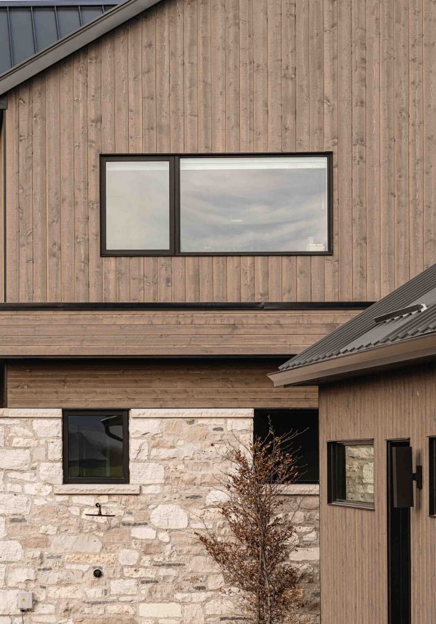 Warm light hits the exterior of a contemporary farmhouse with rich, wood siding and modern lines