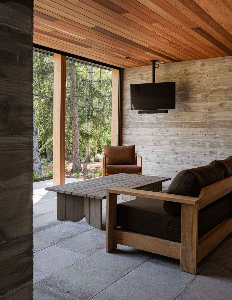 Screened porch of an alpine chalet featuring board formed concrete walls, cedar ceiling and nordic-inspired furniture