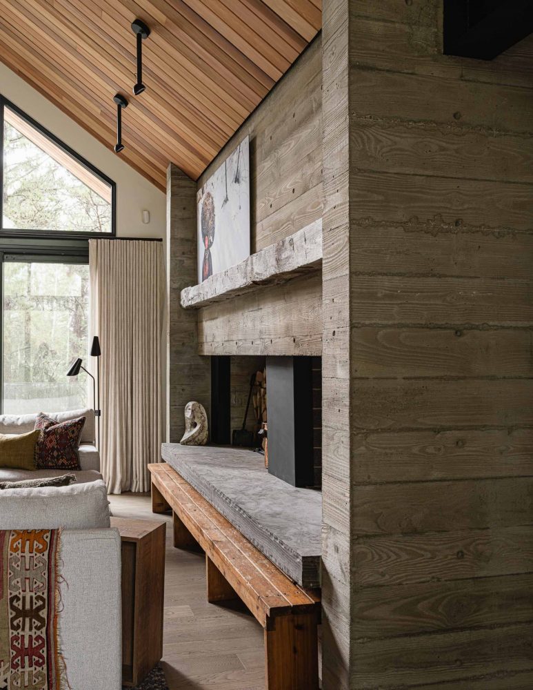Detail of a contemporary board formed concrete fireplace with stone hearth, reclaimed wood mantle and custom steel details
