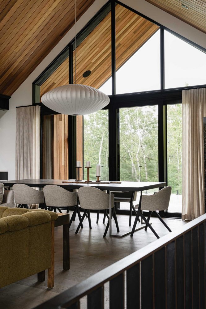 Dining room detail of a contemporary alpine chalet with vaulted ceiling, forested views modern light fixure