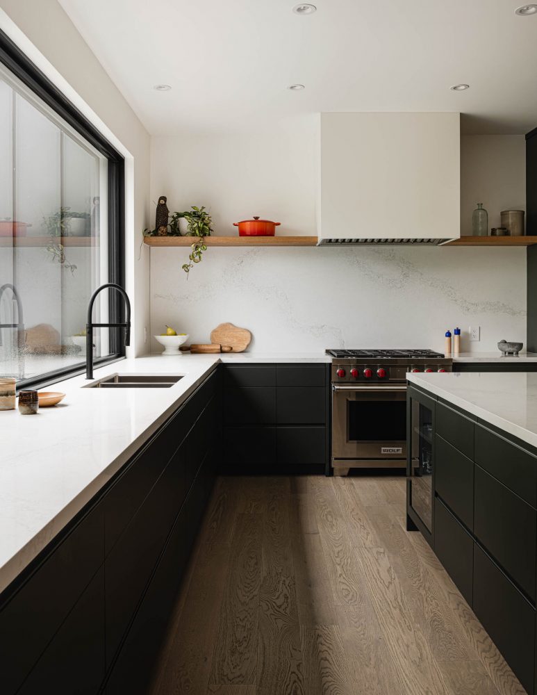 kitchen detail in a modern alpine chalet with sleek black lowers, quartz counters and backsplash and contemporary fixtures