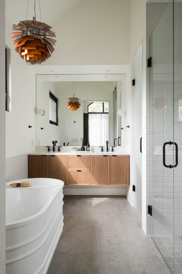 Ensuite bathroom in a modern alpine chalet featuring standing tub, custom oak vanity, and Louis Poulsen artichoke light fixture