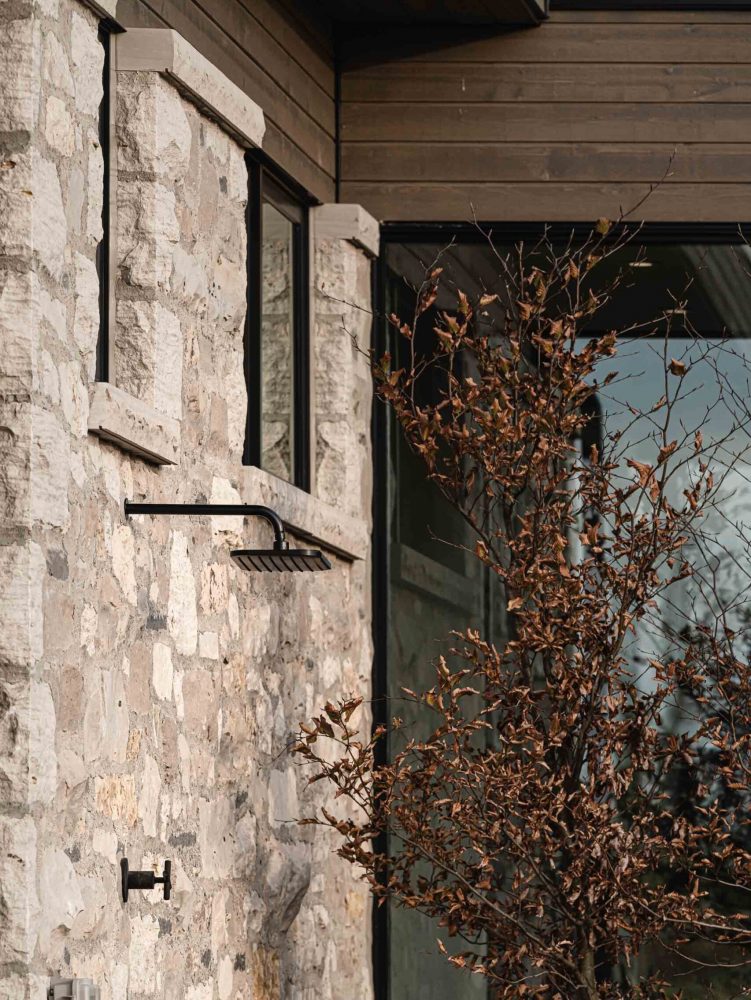 Detail of an outdoor shower, set into the stone wall of a contemporary country home