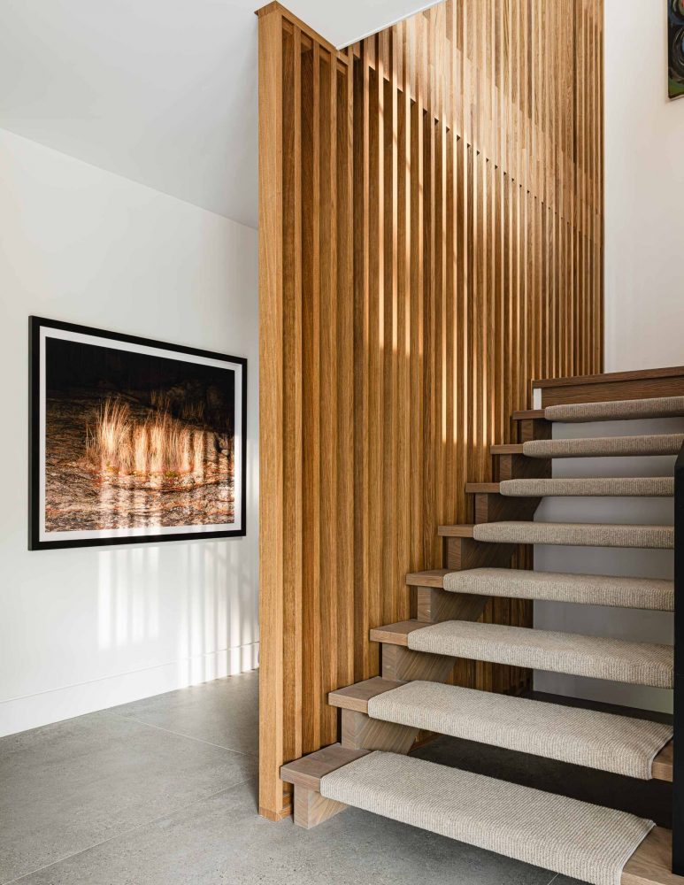 Modern chalet staircase detail with wood slat divider wall, contemporary framed art piece and concrete tile floors