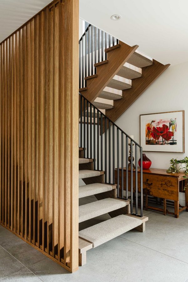Modern staircase detail featuring slated wood dividing wall, custom steel railing and large format concrete tile floors